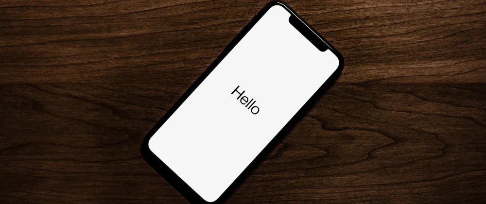 iPhone on a wooden table with text that says "Hello"