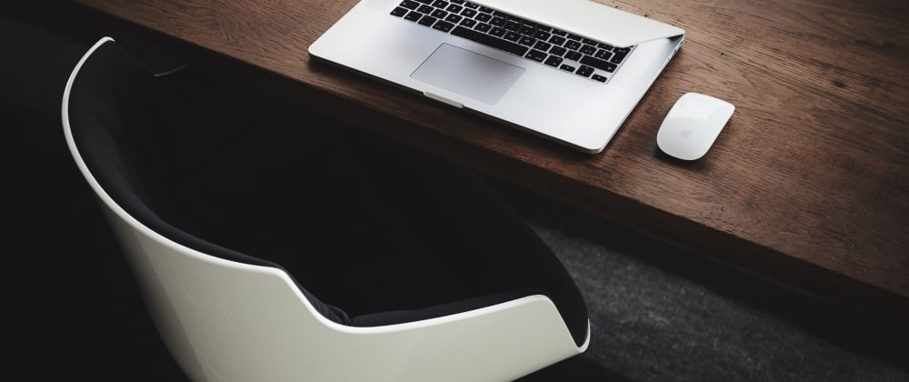 Dark wood desk with modern white and black chair and Macbook