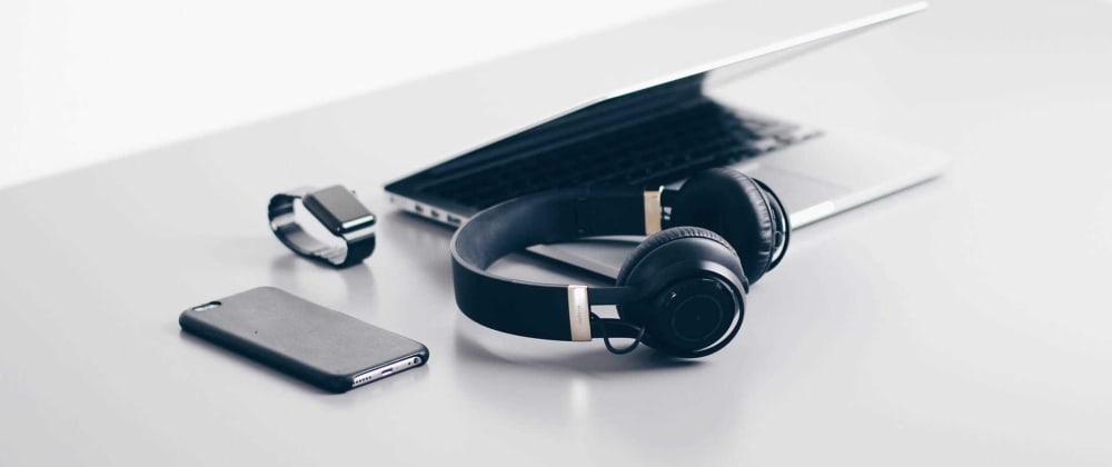 Table with laptop, headphones, smartwatch, and smartphone